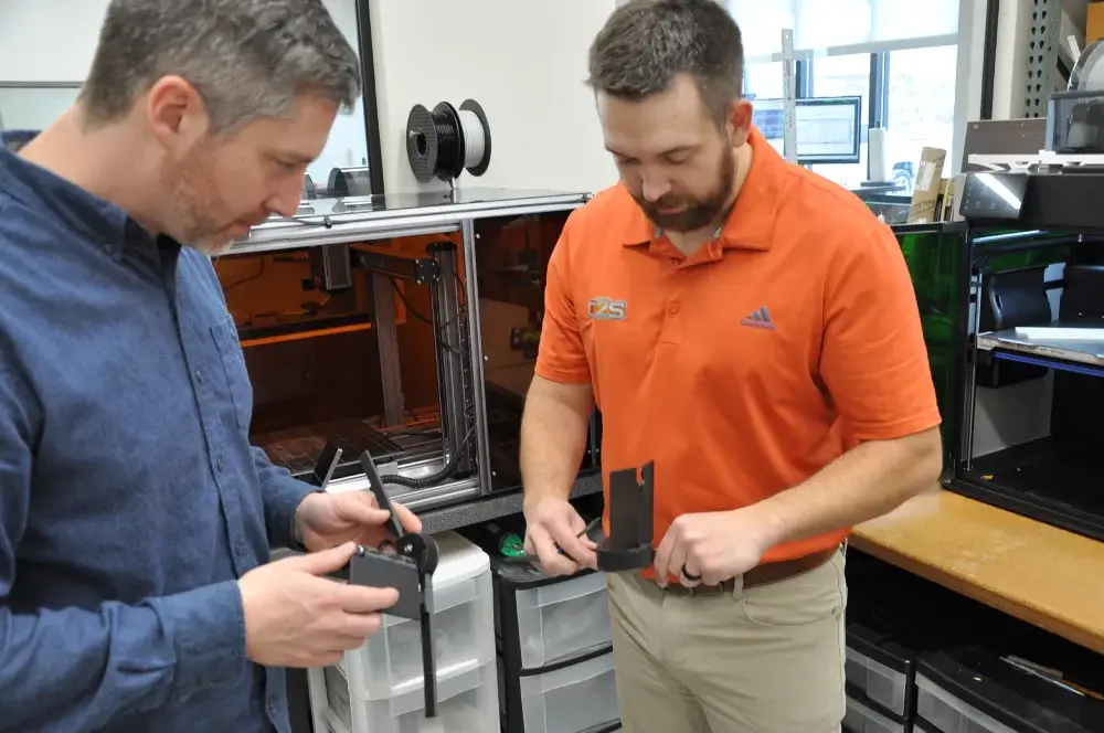 Mechanical-Designers-Collaborating-3D-Prototype-C2S-Lab Two C2S mechanical designers collaborating on a 3D printed prototype for product development and form-fit validation in a lab setting.